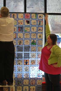 June assists in hanging a quilt at Great American in Cooperstown.